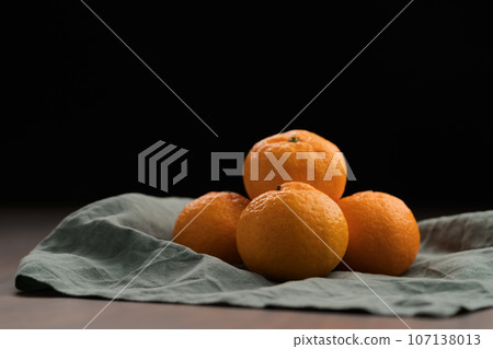 Organic tangerines on a linen napkin on a wood table Organic tangerines on a linen napkin on a wood table 107138013