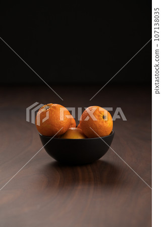 Fresh tangerines in a bowl on a wood table Fresh tangerines in a bowl on a wood table 107138035