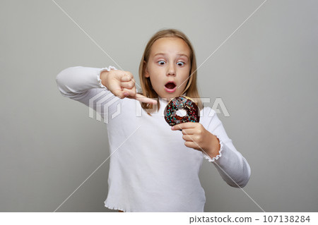 Excited surprised kid girl pointing delicious chocolate donut. Pretty adorable child having fun 107138284