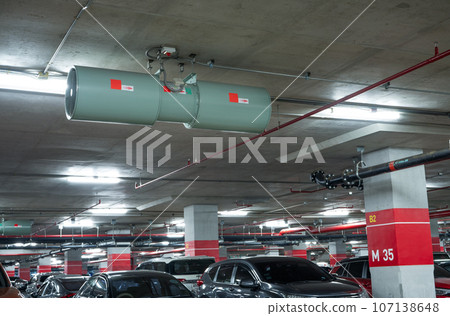Jet fan at underground parking area. Ventilation fan in the parking lot. Air flow system. Ventilation system in underground car parking lot at commercial building. Duct fan air ventilation at mall. Jet fan at underground parking area. Ventilation fan in the parking lot. Air flow system. Ventilation system in underground car parking lot at commercial building. Duct fan air ventilation at mall. 107138648