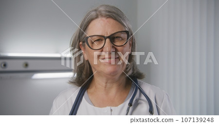 Female mature doctor looks at camera and smiles Female mature doctor looks at camera and smiles 107139248