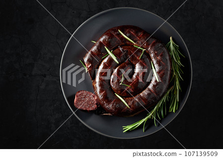 Black pudding or blood sausage with rosemary on a black plate. 107139509