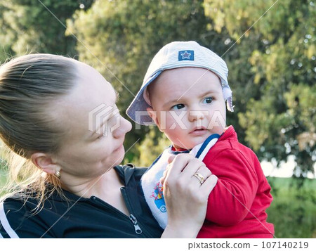 close-up, mother holding a child in her arms in the park 107140219