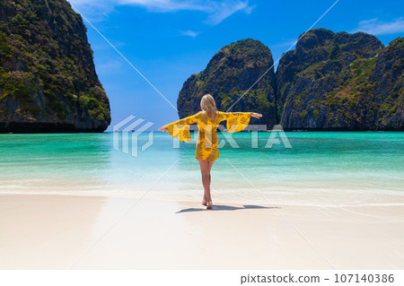 Beautiful young blonde woman in orange dress on a Maya Bay Beach during excursion of phi phi leh island in andaman sea thailand. 107140386