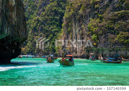 A picturesque beautiful place on the island of Phi Phi Leh - Pi Leh Lagoon is popular for excursions with tourists on traditional Thai fishing boats. Island travel in Thailand. A picturesque beautiful place on the island of Phi Phi Leh - Pi Leh Lagoon is popular for excursions with tourists on traditional Thai fishing boats. Island travel in Thailand. 107140399
