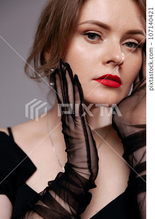 Red-lipped woman in black dress, looks at the camera. Red-lipped woman in black dress, looks at the camera. 107140421