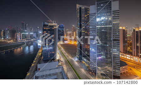 Panorama showing cityscape of skyscrapers in Dubai Business Bay with water canal aerial night 107142800