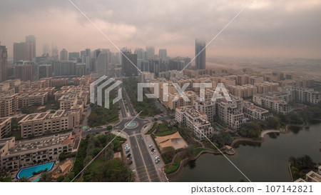 Skyscrapers in Barsha Heights district and low rise buildings in Greens district aerial night to day. Skyscrapers in Barsha Heights district and low rise buildings in Greens district aerial night to day. 107142821