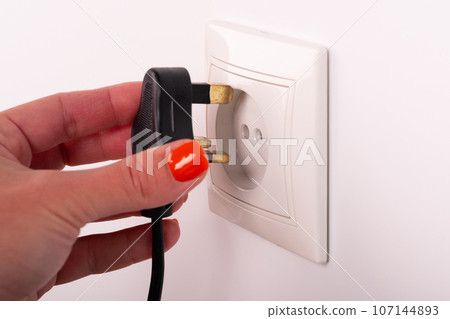 Different standards for electrical outlets. Unsuitable connector and plug in the hand of a person. Incompatibility, concept 107144893