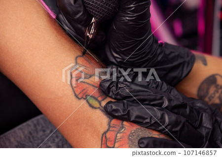Creation of colorful poppies tattoo on female arm using tattooing machine Creation of colorful poppies tattoo on female arm using tattooing machine 107146857