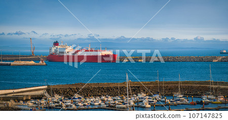 Panoramic shot of LNG or liquified natural gas carrier moored by industrial pier on hazy evening. Alternative gas supply, commercial freight, energy crisis, regasification, diversification, fuel and 107147825