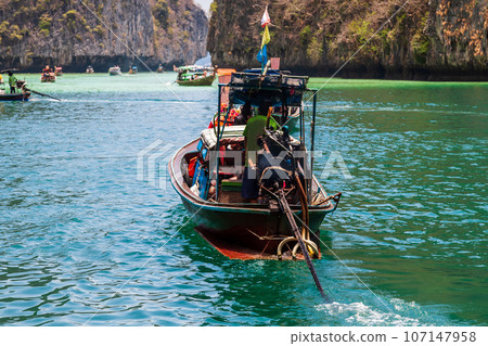 A picturesque beautiful place on the island of Phi Phi Leh - Pi Leh Lagoon is popular for excursions with tourists on traditional Thai fishing boats. Island travel in Thailand. A picturesque beautiful place on the island of Phi Phi Leh - Pi Leh Lagoon is popular for excursions with tourists on traditional Thai fishing boats. Island travel in Thailand. 107147958
