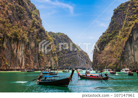 A picturesque beautiful place on the island of Phi Phi Leh - Pi Leh Lagoon is popular for excursions with tourists on traditional Thai fishing boats. Island travel in Thailand. A picturesque beautiful place on the island of Phi Phi Leh - Pi Leh Lagoon is popular for excursions with tourists on traditional Thai fishing boats. Island travel in Thailand. 107147961