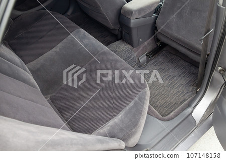 Close-up on rear seats with velours fabric upholstery in the interior of an old car in gray after dry cleaning. Auto service industry Close-up on rear seats with velours fabric upholstery in the interior of an old car in gray after dry cleaning. Auto service industry 107148158