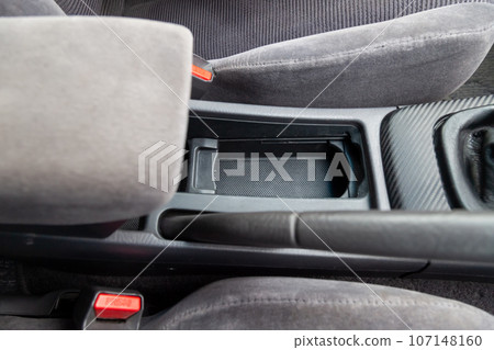 Interior view with fabric seats and cupholders in armrest of black used car stands in the showroom after dry washing before sale Interior view with fabric seats and cupholders in armrest of black used car stands in the showroom after dry washing before sale 107148160