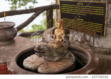 sculpture of a Buddhist woman on a crocodile near the statue of a big buddha in thailand on the island of phuket 107148182