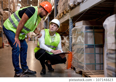 Managers men workers doing stocktaking of product management on shelves in warehouse Managers men workers doing stocktaking of product management on shelves in warehouse 107148823