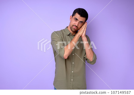 serious handsome man showing sleeping gesture, lying on folded hands serious handsome man showing sleeping gesture, lying on folded hands 107149587