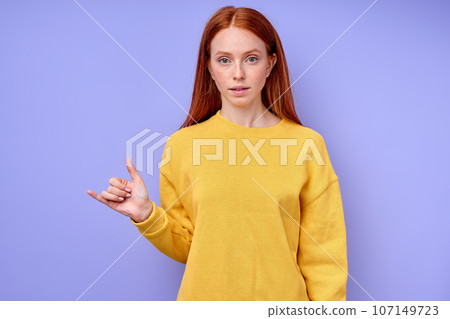 serious confident redhead woman in yellow stylish sweater demonstrating letter Y serious confident redhead woman in yellow stylish sweater demonstrating letter Y 107149723