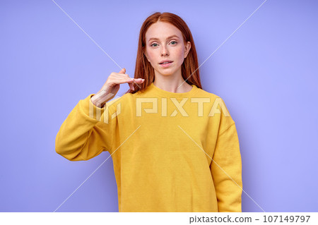 beautiful redhead girl showing letter F on blue background beautiful redhead girl showing letter F on blue background 107149797