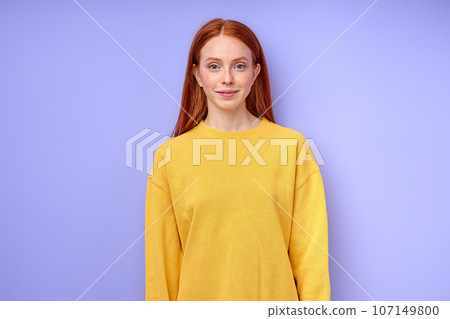 Portrait of young redhead female in casual yellow shirt posing at camera smiling Portrait of young redhead female in casual yellow shirt posing at camera smiling 107149800