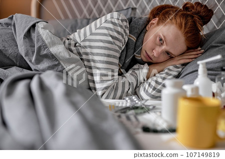 sick pale redhead girl cannot sleep, fall asleep as she has terrible headache 107149819