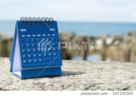 Blue July 2024 calendar on blurred background of blue ocean. New Year Concept 107150369