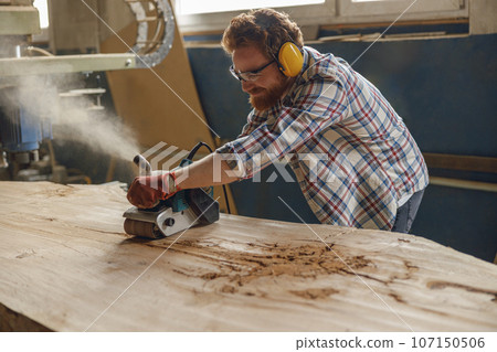 Professional male carpenter using electric sander for wood. Manufacture of wood products Professional male carpenter using electric sander for wood. Manufacture of wood products 107150506