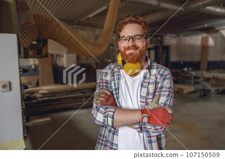 Smiling woodworker with crossed hands standing on the background on carpentry workshop Smiling woodworker with crossed hands standing on the background on carpentry workshop 107150509