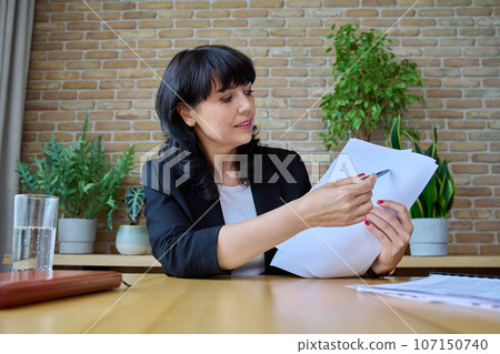 Talking mature businesswoman with documents looking in webcam 107150740