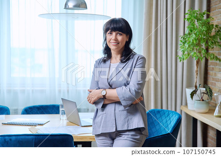 Portrait of beautiful mature business woman with crossed arms in office 107150745
