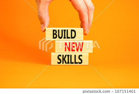 Build new skills symbol. Concept word Build new skills on beautiful wooden block. Businessman hand. Beautiful orange table orange background. Business, education build new skills concept. Copy space. 107151401