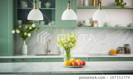 Interior of modern classic kitchen with green facades. Marble countertop and backsplash, flowers in vases, fresh fruits, various crockery, pendant lamps. Contemporary home design. Interior of modern classic kitchen with green facades. Marble countertop and backsplash, flowers in vases, fresh fruits, various crockery, pendant lamps. Contemporary home design. 107151774