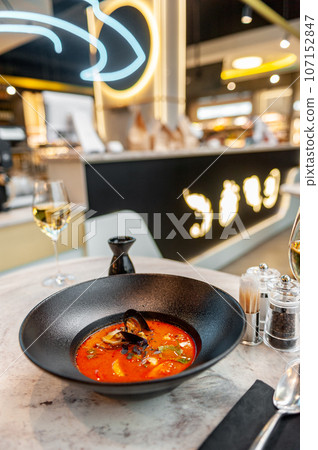 Tom yam in a black plate on a table in a restaurant Tom yam in a black plate on a table in a restaurant 107152847