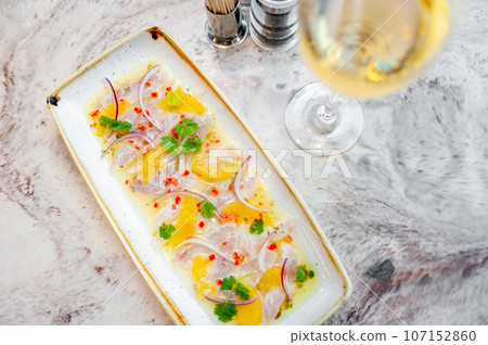 Sea bass ceviche with orange and mango salsa on a marble table in a restaurant Sea bass ceviche with orange and mango salsa on a marble table in a restaurant 107152860