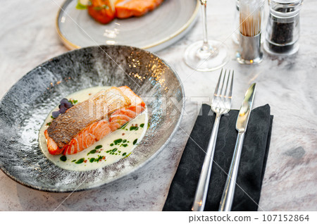 Salmon fillet in cream sauce with herbs on a marble table in a restaurant 107152864
