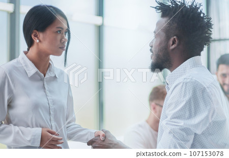 Business Handshake - business people shaking hands. Handshake between business man and woman indoors. Business Handshake - business people shaking hands. Handshake between business man and woman indoors. 107153078
