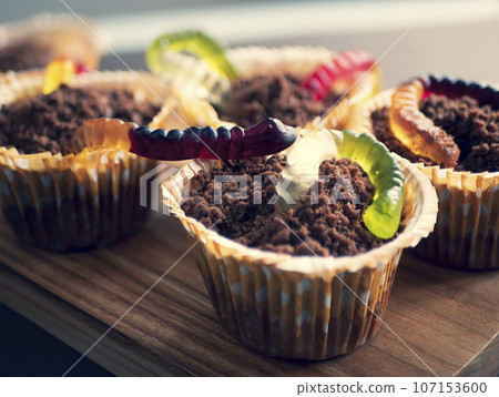 Halloween sweet chocolate cupcakes with jellies reminiscent of worms in the soil. Food for children party Halloween sweet chocolate cupcakes with jellies reminiscent of worms in the soil. Food for children party 107153600