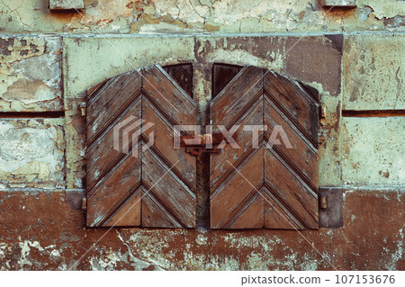 Old vintage small window with closed antique wooden shutters. Old vintage small window with closed antique wooden shutters. 107153676