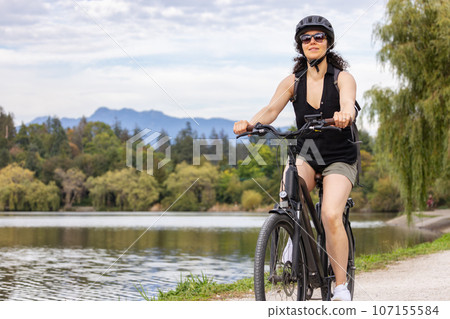 Fit Caucasian Woman riding an Electric Bicycle on a trail in Stanley Park, Downtown Vancouver, British Columbia, Canada 107155584