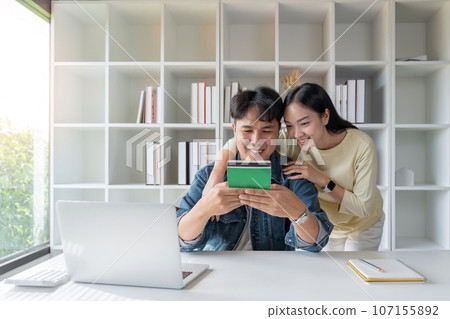 Happy Asian couple are looking at account book to plan for invest and family finance Happy Asian couple are looking at account book to plan for invest and family finance 107155892