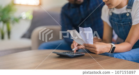 Close up of indian couple hand calculate budget or expense by hold bill at home concept of investment, budget calculation and financial plan Close up of indian couple hand calculate budget or expense by hold bill at home concept of investment, budget calculation and financial plan 107155897
