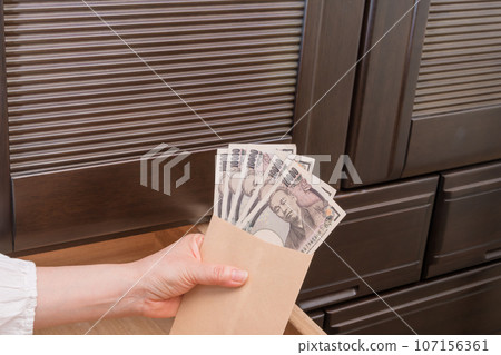 [A housewife hides a 10,000-yen bill in an envelope in the chest drawer] 107156361