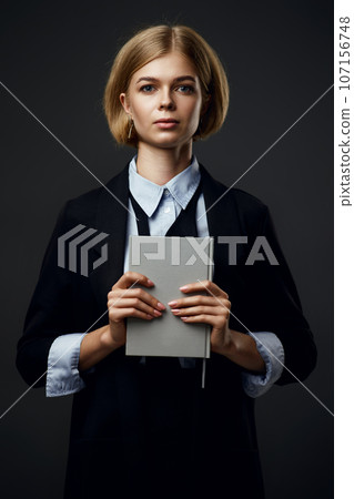trendy blonde businesswoman holding notepad on black background 107156748