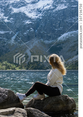 Young woman enjoying nature in Morskie Oko Snowy Mountain Hut in Polish Tatry mountains Zakopane Poland. Naturecore aesthetic beautiful green hills. Mental and physical wellbeing Travel outdoors 107156750