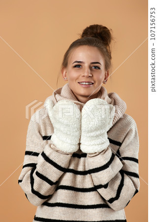 happy young woman in wool sweater and mittens 107156753