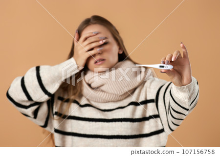 woman with high fever measuring body temperature by thermometer 107156758