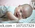 Asian baby boy smiling on cozy bed 107157329