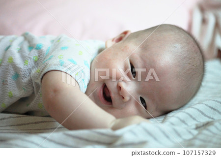 Asian baby boy smiling on cozy bed 107157329