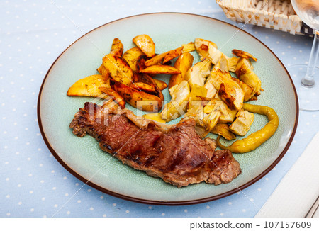 Tasty baked beef steak with potatoes and artichokes 107157609